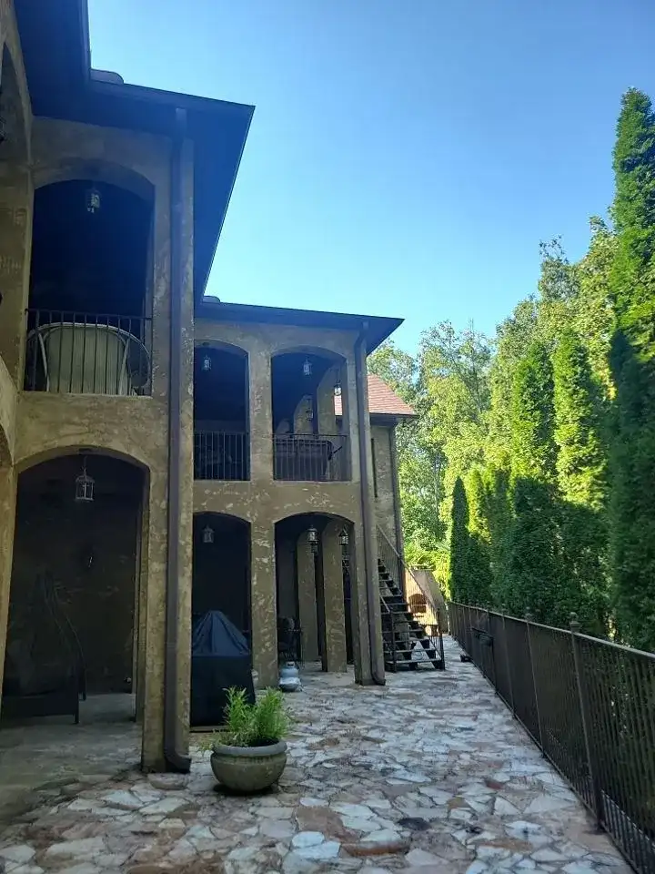 A large, two-story brick building with a black awning and a patio.