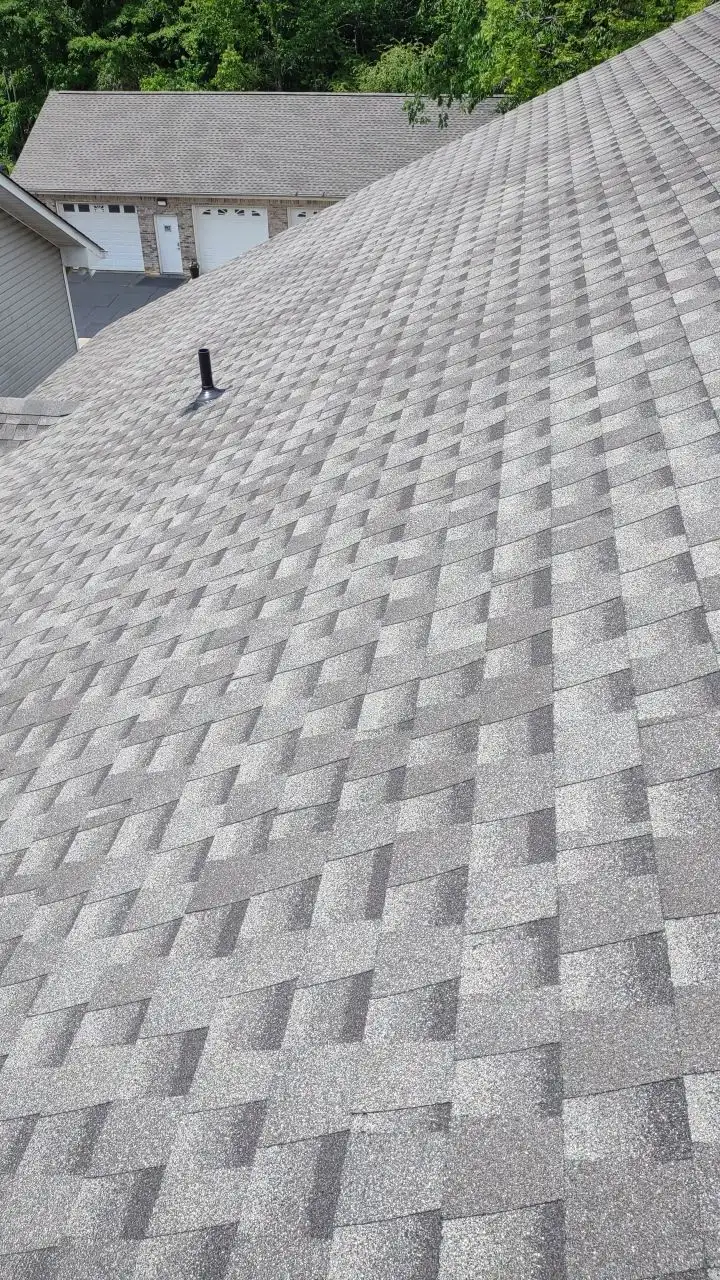 A roof with a black chimney and a grey shingle.