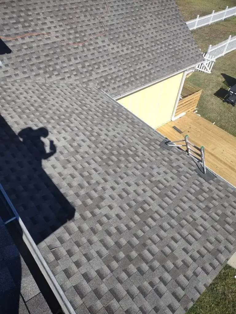 A man taking a picture of a roof with a cell phone.