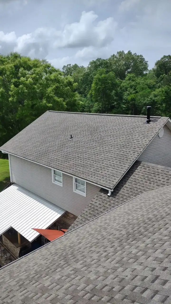 A white house with a grey roof and a chimney.